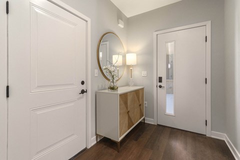 a living room with white doors and a mirror and a dresser with a mirror